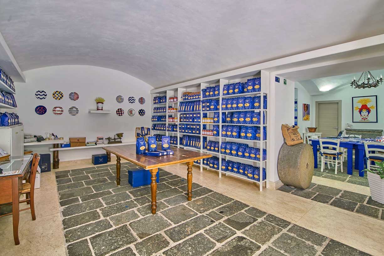 Der Innenraum des Pastificio Gentile Ladens, gefüllt mit Regalen voller blauer Pasta-Packungen, die Vielfalt und Qualität der Produkte des Traditionsunternehmens zeigen