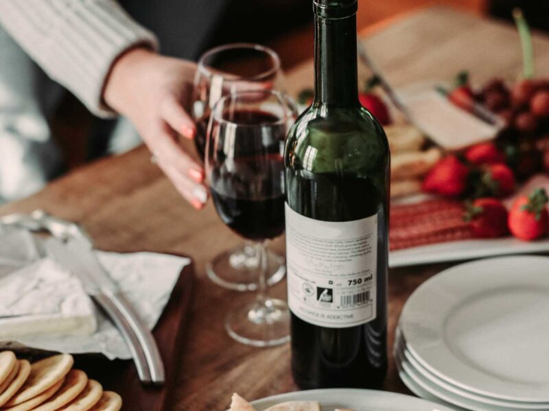 Ein gemütliches Abendessen mit Brot, Käse, frischen Früchten und einer Flasche Primitivo-Wein – der perfekte Moment für Genießer.