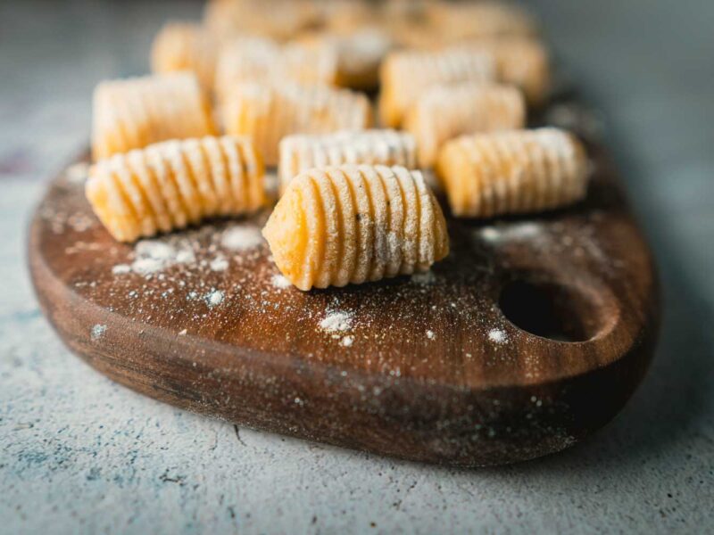 Gnocchi auf dunklem Holzbrett mit Mehl bestäubt in Nahaufnahme