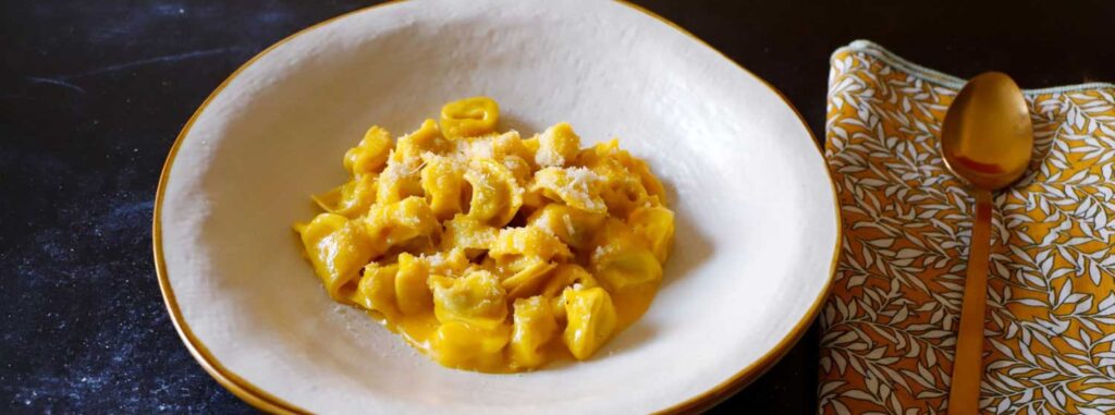 Teller mit cremigen, frisch zubereiteten Tortellini, angerichtet mit geriebenem Parmesan.