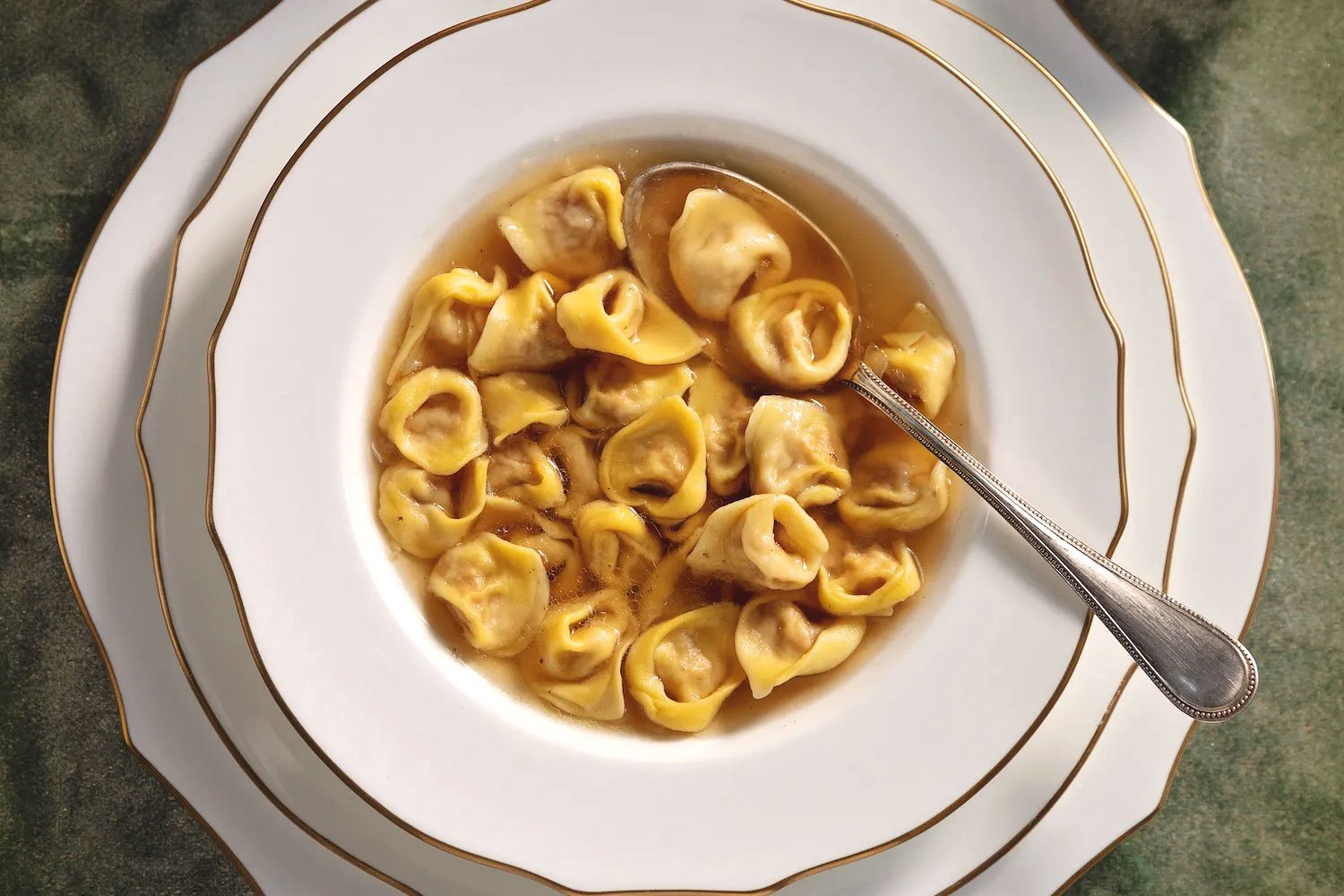 Traditionelle Tortellini in einer klaren Fleischbrühe, serviert in einem eleganten Suppenteller.