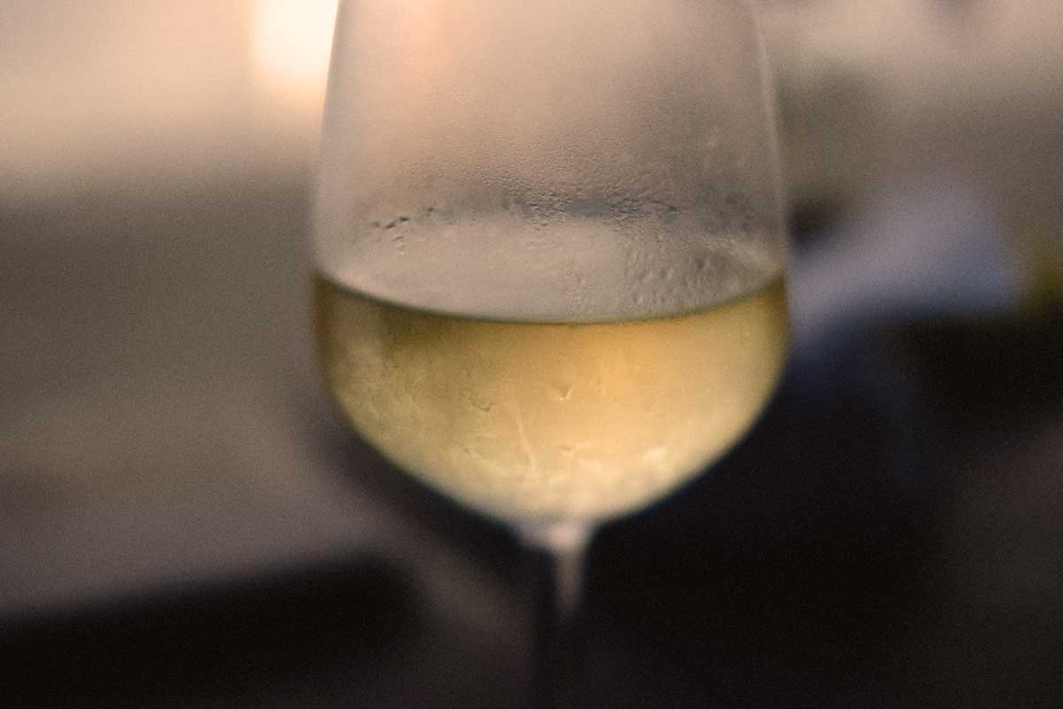 Makroaufnahme eines beschlagenen Weißweinglases mit Gavi-Wein, perfekt gekühlt für den sommerlichen Weingenuss.